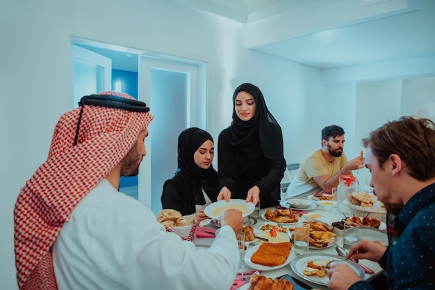 Familia musulmana cenando Iftar bebiendo agua para romper la fiesta. Comer comida tradicional durante el mes de fiesta del Ramadán en casa. La comida y bebida halal islámica en el hogar moderno.