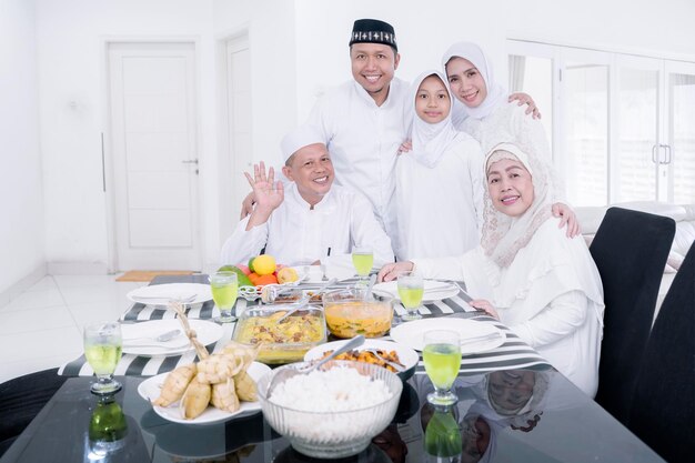 Familia musulmana comiendo mientras sonríe a la cámara