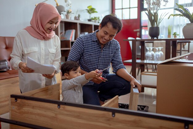 familia musulmana e hijo ensamblando muebles nuevos en casa juntos
