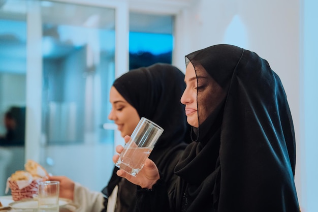 Familia musulmana de Eid Mubarak cenando Iftar bebiendo agua para romper la fiesta. Comer comida tradicional durante el mes de fiesta del Ramadán en casa. La comida y bebida halal islámica en la isla occidental moderna