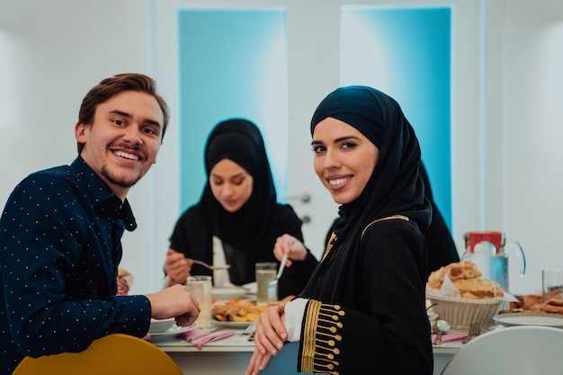 Familia musulmana de Eid Mubarak cenando Iftar tomando fotos con un smartphone mientras come comida tradicional durante el mes de fiesta del Ramadán en casa. La familia islámica de comida y bebida halal islámica.