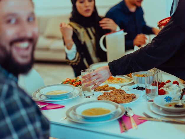 Foto familia musulmana de eid mubarak cenando iftar tomando fotos con un smartphone mientras come comida tradicional durante el mes de fiesta del ramadán en casa. la familia islámica de comida y bebida halal islámica.