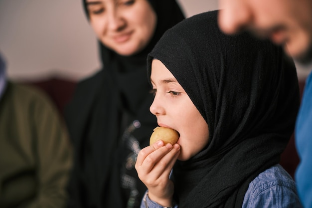 Familia musulmana feliz cenando iftar durante el Ramadán una hija comiendo comida