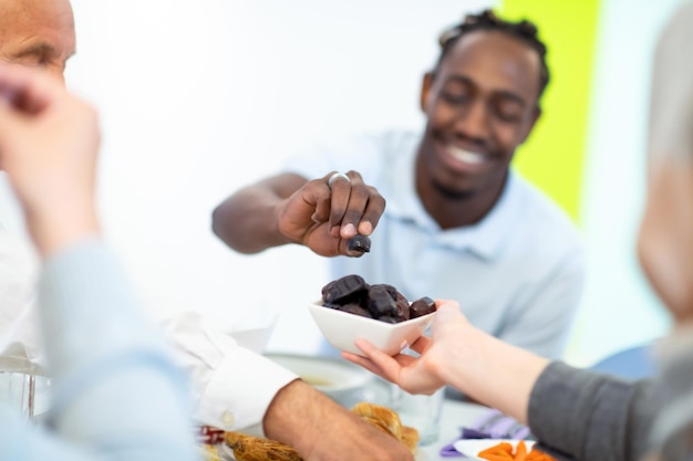 familia musulmana multiétnica moderna compartiendo un tazón de dátiles mientras disfrutan de una cena iftar juntos durante una fiesta de ramadán en casa