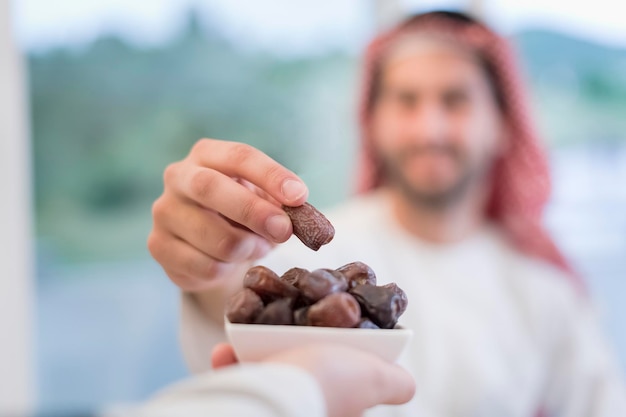 familia musulmana multiétnica moderna que comparte un tazón de dátiles mientras disfruta de una cena iftar juntos durante una fiesta de Ramadán en casa.