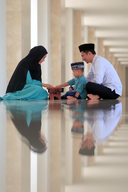 Una familia musulmana se sienta en el suelo de una mezquita.