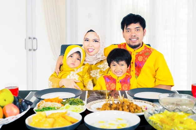 Familia musulmana sonriendo a la cámara en el comedor