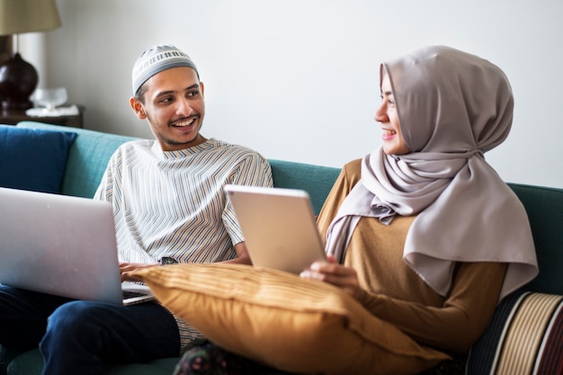 Familia musulmana utilizando dispositivos digitales en casa