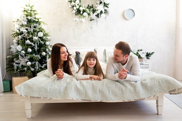 Família na cama em casa perto da árvore de Natal
