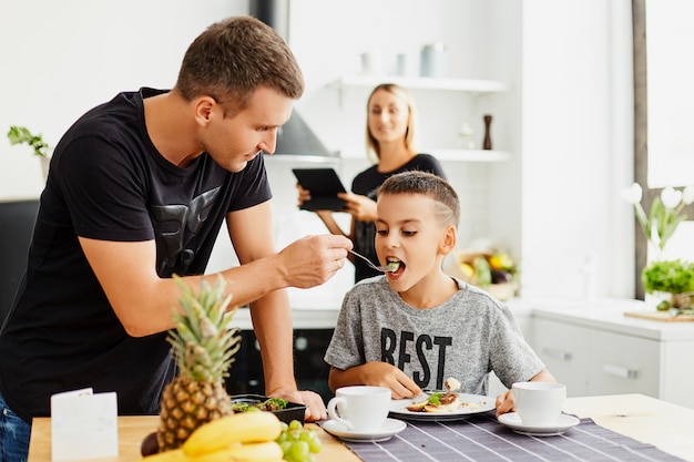 Família na cozinha comendo comida