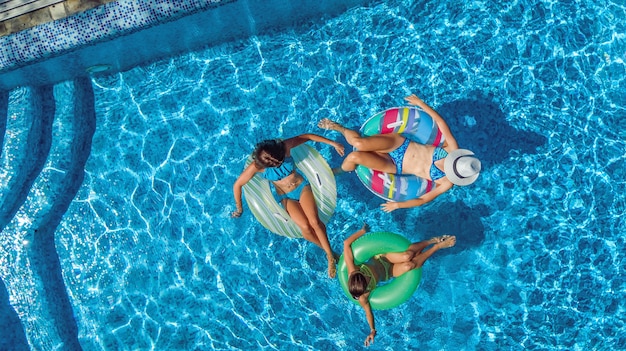 Família na piscina aérea zangão vista de cima, feliz mãe e filhos nadam em anéis de espuma inflável e se divertem na água em férias em família, férias tropicais no resort