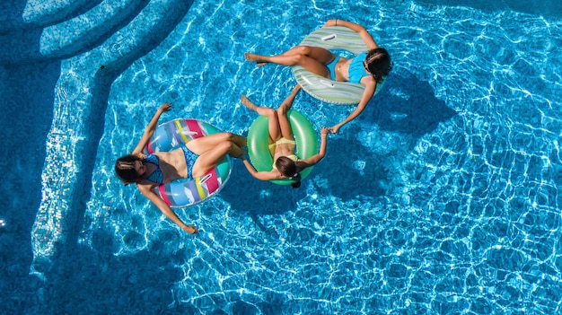 Família na piscina vista aérea de cima, feliz mãe e filhos nadam em anéis de espuma inflável e se divertem na água em férias em família, férias tropicais no resort