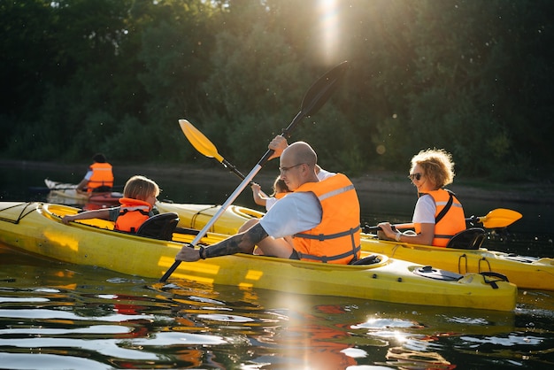 Familia en naranja chalecos salvavidas en kayak en dos botes en un río