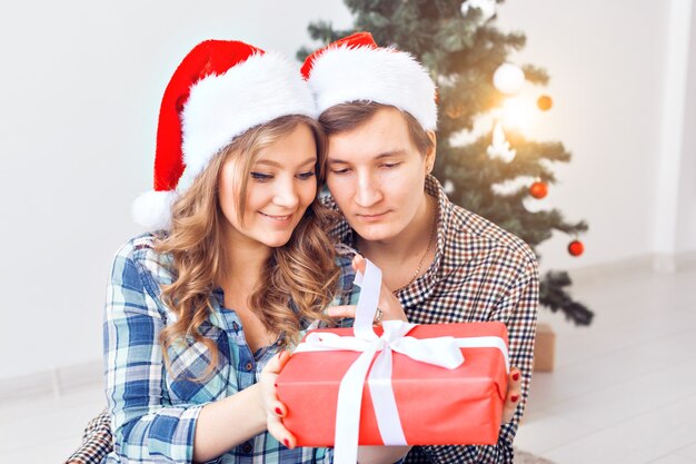 Família, Natal, férias de inverno e conceito de pessoas - casal feliz abraçando perto de árvore de Natal em casa.