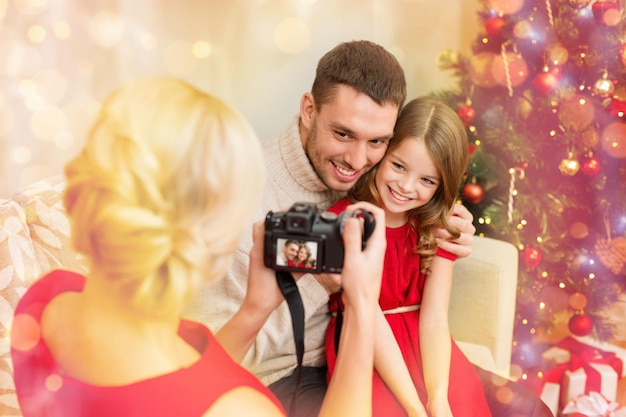 família, natal, natal, inverno, felicidade e conceito de pessoas - mãe tirando foto de pai e filha sorridentes