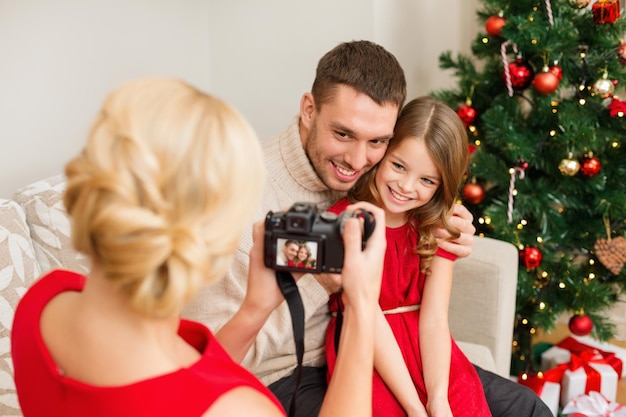 família, natal, natal, inverno, felicidade e conceito de pessoas - mãe tirando foto de pai e filha sorridentes