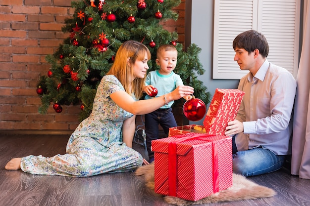 Familia de Navidad con bebé. Regalo de apertura de niño feliz. árbol de Navidad