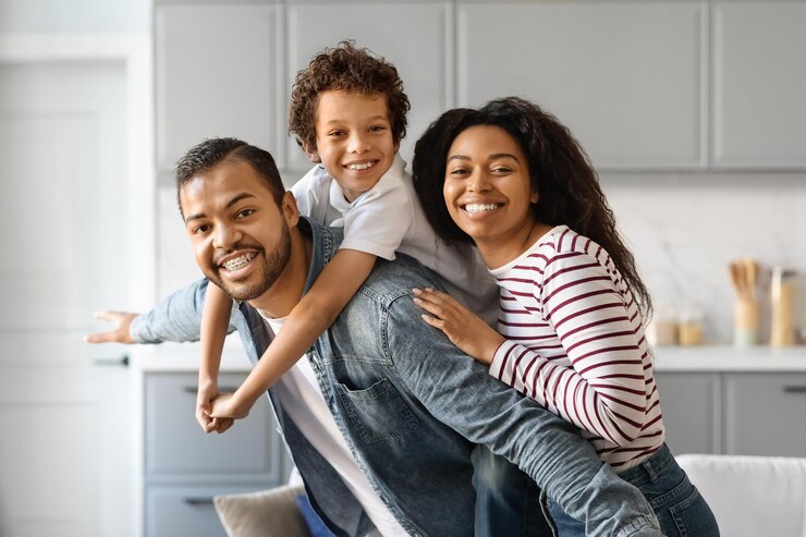 Foto familia negra alegre con un hijo pequeño abrazando y sonriendo a la cámara