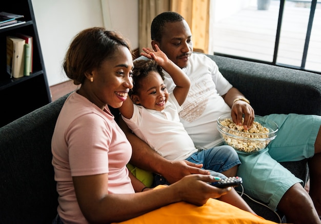 Familia negra comiendo palomitas de maíz mientras ve la película en casa