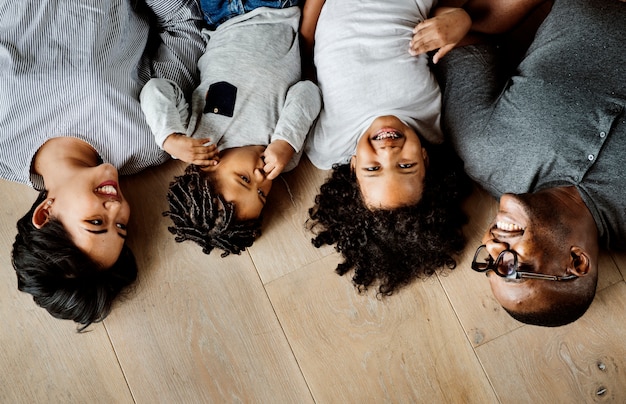 Família negra deitado no espaço de design de piso de madeira