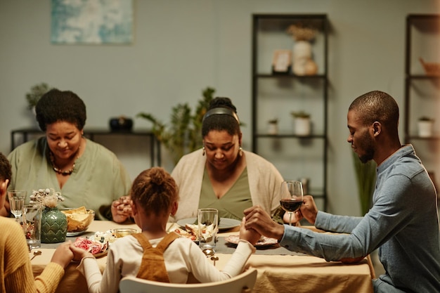 Familia negra diciendo gracias en la cena