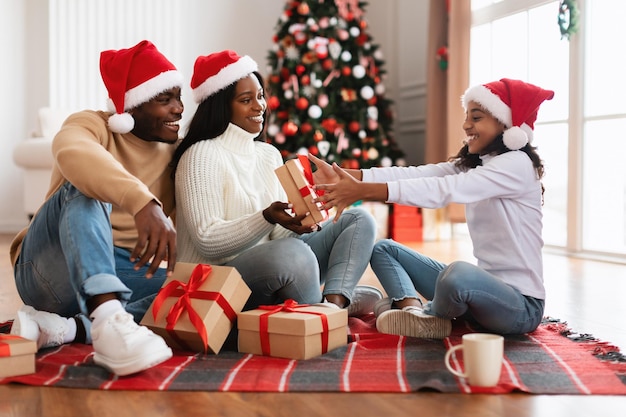 Família negra feliz comemorando o natal trocando presentes