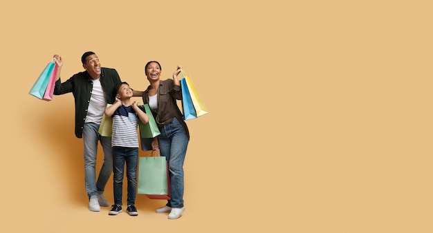 Família negra feliz curtindo fazer compras juntos no espaço de cópia bege