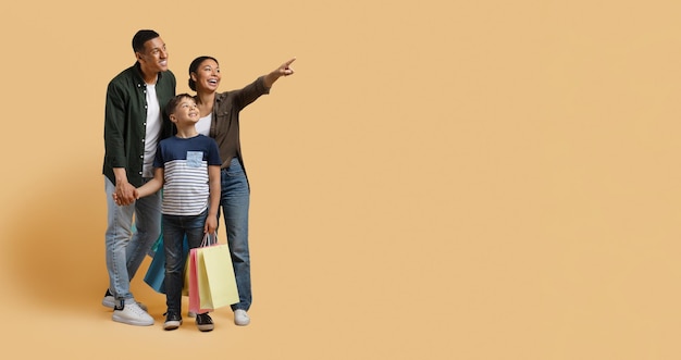 Familia negra feliz disfrutando de ir de compras juntos apuntando al espacio de copia