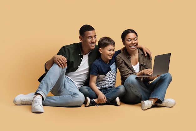 Familia negra feliz eligiendo películas en línea en una laptop