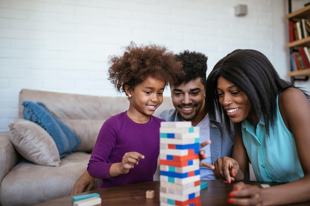 Una familia negra feliz jugando una ronda de jenga con su encantadora hija