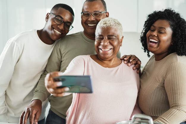 Família negra feliz tirando uma selfie com o celular na cozinha de casa