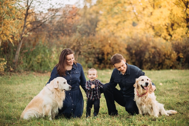 Familia con un niño y dos golden retrievers en un parque de otoño