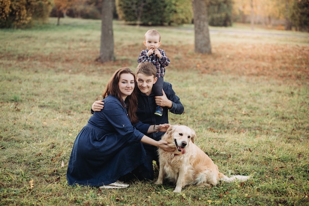 Foto familia con un niño y un golden retriever en un parque de otoño