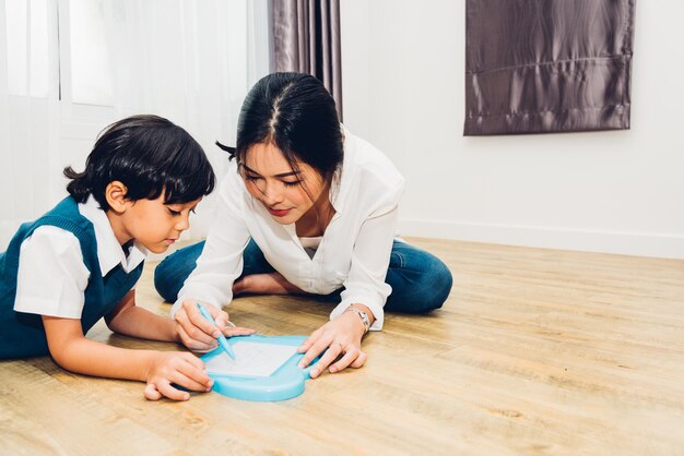 Familia niño niño niño hijo jardín de infantes y hermosa madre educación enseñando a dibujar juntos en la habitación interior de la casa