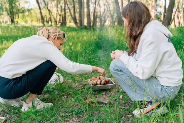 Familia con niño pequeño adolescente y abuela haciendo barbacoa en la naturaleza Parrilla de barbacoa de un solo uso