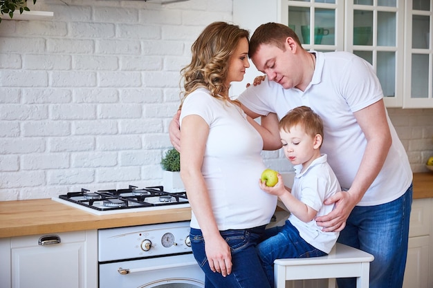 Familia con un niño pequeño y una joven embarazada en la cocina