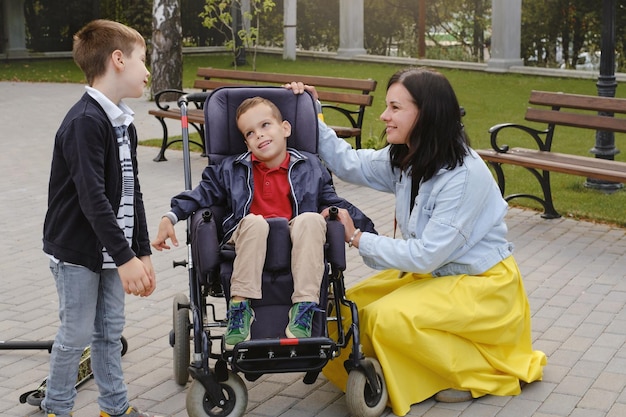 Familia con niño que tiene parálisis cerebral en silla de ruedas con madre hermano