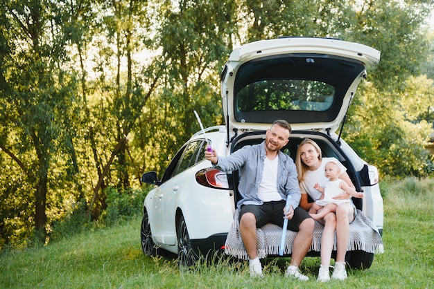 Familia con niño sentado en el maletero del coche