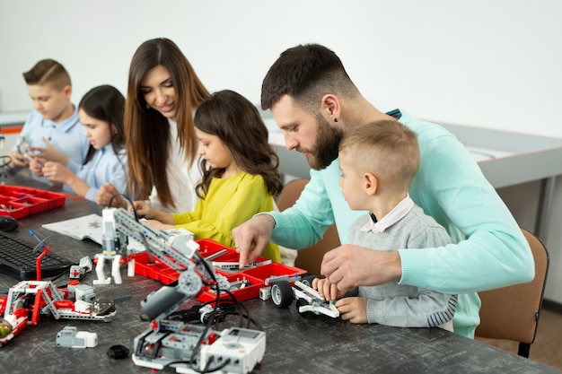 Una familia con niños en un club de robótica fabrica un robot controlado por un constructor.