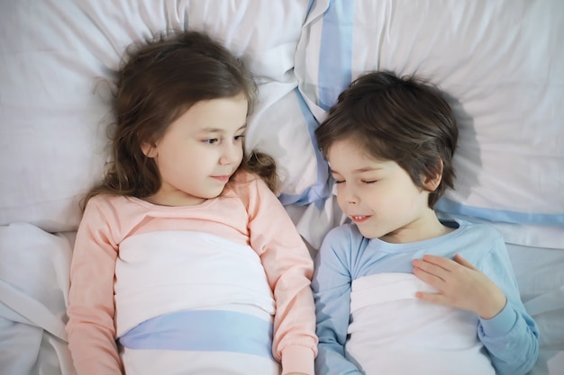 Una familia con niños divirtiéndose en la cama bajo las mantas durante las vacaciones de Navidad.