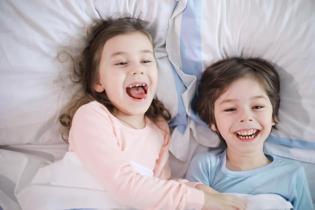 Una familia con niños divirtiéndose en la cama bajo las sábanas durante las vacaciones de Navidad