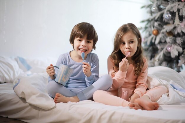 Una familia con niños divirtiéndose en la cama bajo las sábanas durante las vacaciones de Navidad