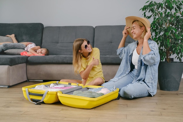 Foto familia con niños empacando una maleta amarilla para viajar juntos