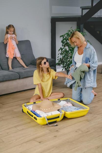 Familia con niños empacando una maleta amarilla para viajar juntos