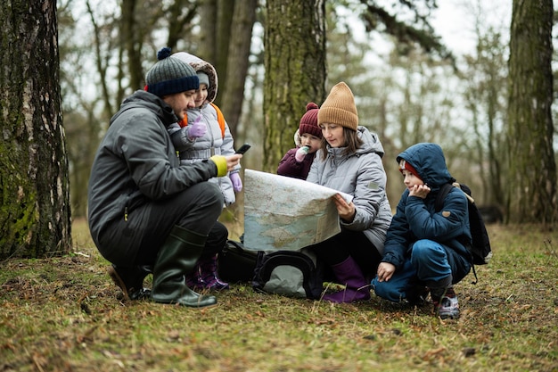 Familia y niños con mapa en el bosque.