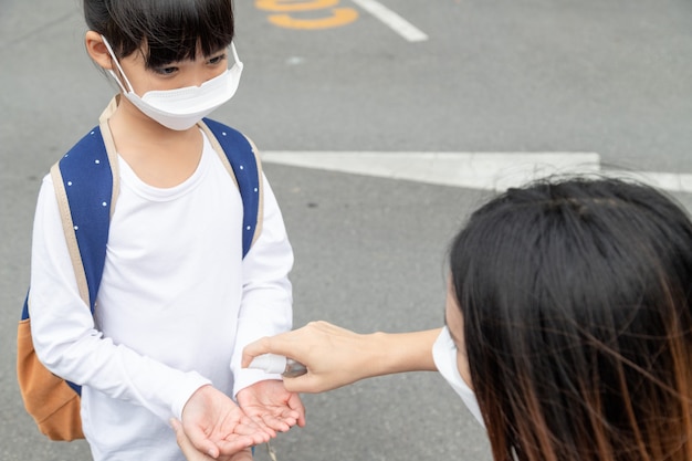 Familia con niños en la mascarilla en un centro comercial. Madre e hija usan mascarilla durante el brote de coronavirus y gripe. Protección contra virus y enfermedades, desinfectante de manos en un lugar público lleno de gente.