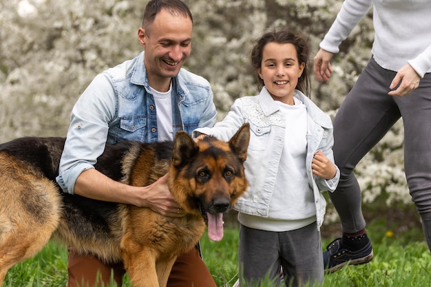 Familia con niños pequeños y perros al aire libre en el huerto en primavera.