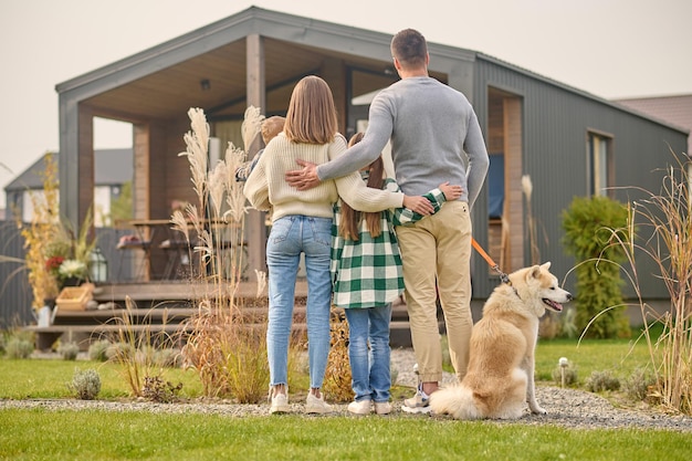 Familia con niños y perro de pie de espaldas a la cámara