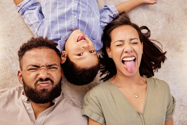 Família no chão e diversão em um tapete na sala de estar com pessoas alegres e brincalhonas mostrando diferentes expressões faciais retrato de família feliz e humor de criança e pais no chão de cima