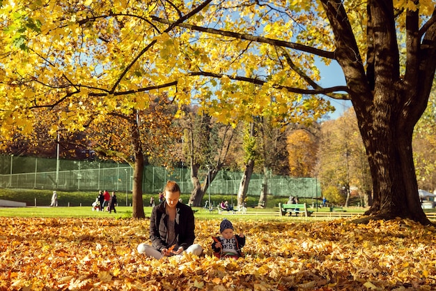 Família no parque de outono. Mãe brincando com o filho na natureza. Mãe e filho pequeno felizes juntos